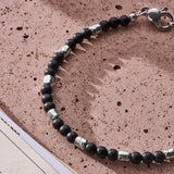 Natural Black Onyx bracelet with 925 sterling silver nuggets styled on a textured surface