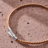 Orange and off-white braided organic cotton bracelet with 925 sterling silver clasp styled on the wrist