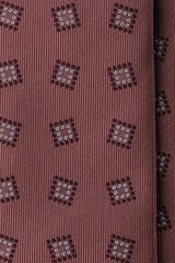 Close-up of woven medallion pattern on terracotta brown silk jacquard tie.