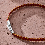 Burgundy and yellow stitched Italian textile bracelet with 925 sterling silver clasp styled on a stone surface