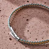 Turquoise and light beige stitched Italian textile bracelet with 925 sterling silver clasp styled on a stone surface