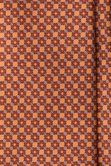 Close-up of the printed silk fabric with salmon, orange and light blue butterfly chain motifs.
