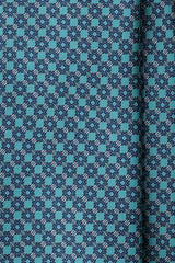 Close-up of the printed silk fabric with turquoise, petrol and pink butterfly chain motifs.