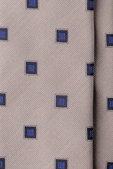 Close-up of beige silk jacquard fabric with royal blue geometric square motifs.