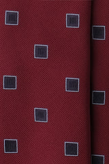 Close-up of bordeaux silk jacquard fabric with navy geometric square motifs.