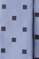 Close-up of light blue silk jacquard fabric with navy geometric square motifs.