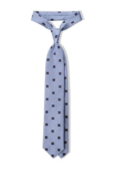 Light blue and navy geometric square silk jacquard tie, tied in a clean knot.