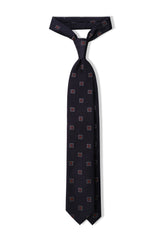 Navy and red geometric square silk jacquard tie, tied in a clean knot.