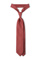 Red horsebit printed silk tie, tied in a clean knot.