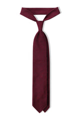 Burgundy plain grenadine shantung silk tie, tied in a knot.