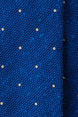Close-up of the azure blue grenadine shantung silk texture with white polka dots.