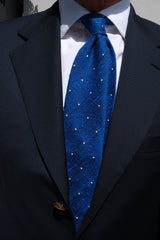 Model styling the azure blue and white polka dot grenadine shantung silk tie with a tailored outfit.