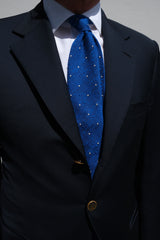 Side view of a model wearing the azure blue and white polka dot grenadine shantung silk tie.