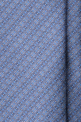 Close-up of the printed silk fabric with light blue, navy and white stirrup chain motifs.