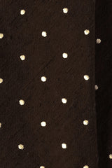 Close-up of the textured brown shantung silk fabric with polka dots.