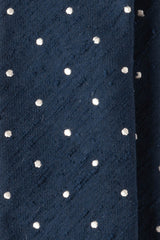 Close-up of the textured navy shantung silk fabric with polka dots.