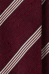 Close-up of the textured bordeaux grenadine shantung silk fabric with stripes.