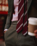 Model styling the bordeaux striped grenadine shantung silk tie with tailored clothing.