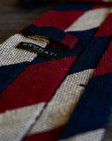 Burgundy, navy and beige striped grenadine shantung silk tie displayed in a styled setting.