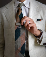 Model styling the green, beige and mustard striped grenadine shantung silk tie with tailored clothing.