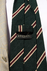 Close-up of the back of the forest, beige and burgundy striped silk shantung tie, showing the Brunati Como label.