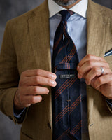 Model adjusting the navy and brown striped silk shantung tie.