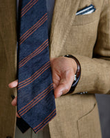 Model holding the navy and brown striped silk shantung tie in hand.